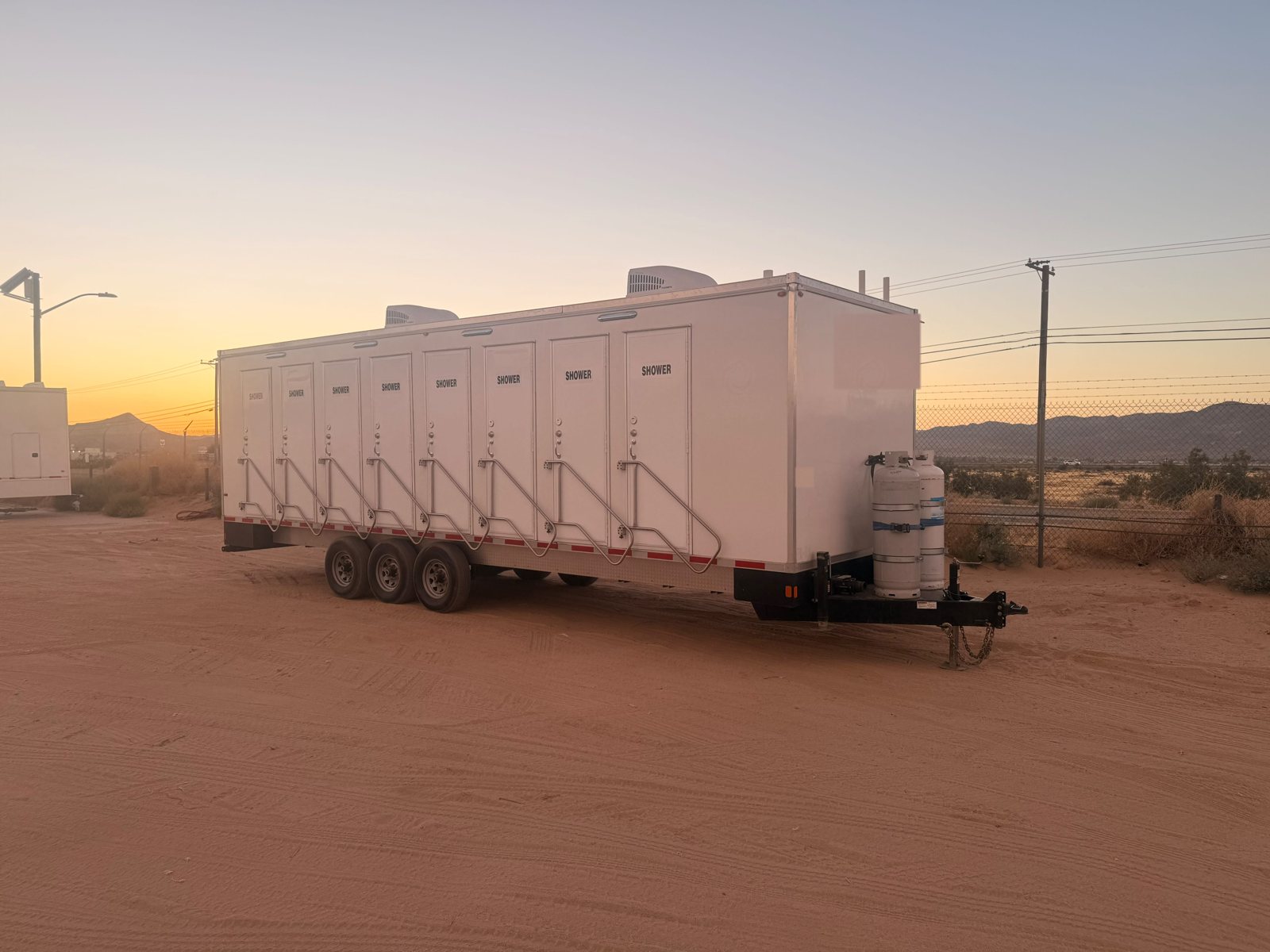 8-station shower trailer with all doors marked SHOWER, stairs and propane tanks at the tongue, available for rent in Boise, ID