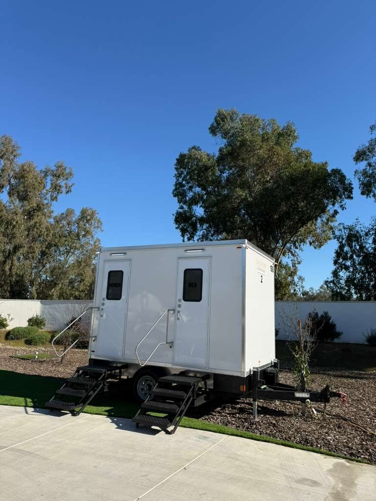 A Lavatory 2-Station restroom trailer beside a concrete walkway and new landscaping in Clovis
