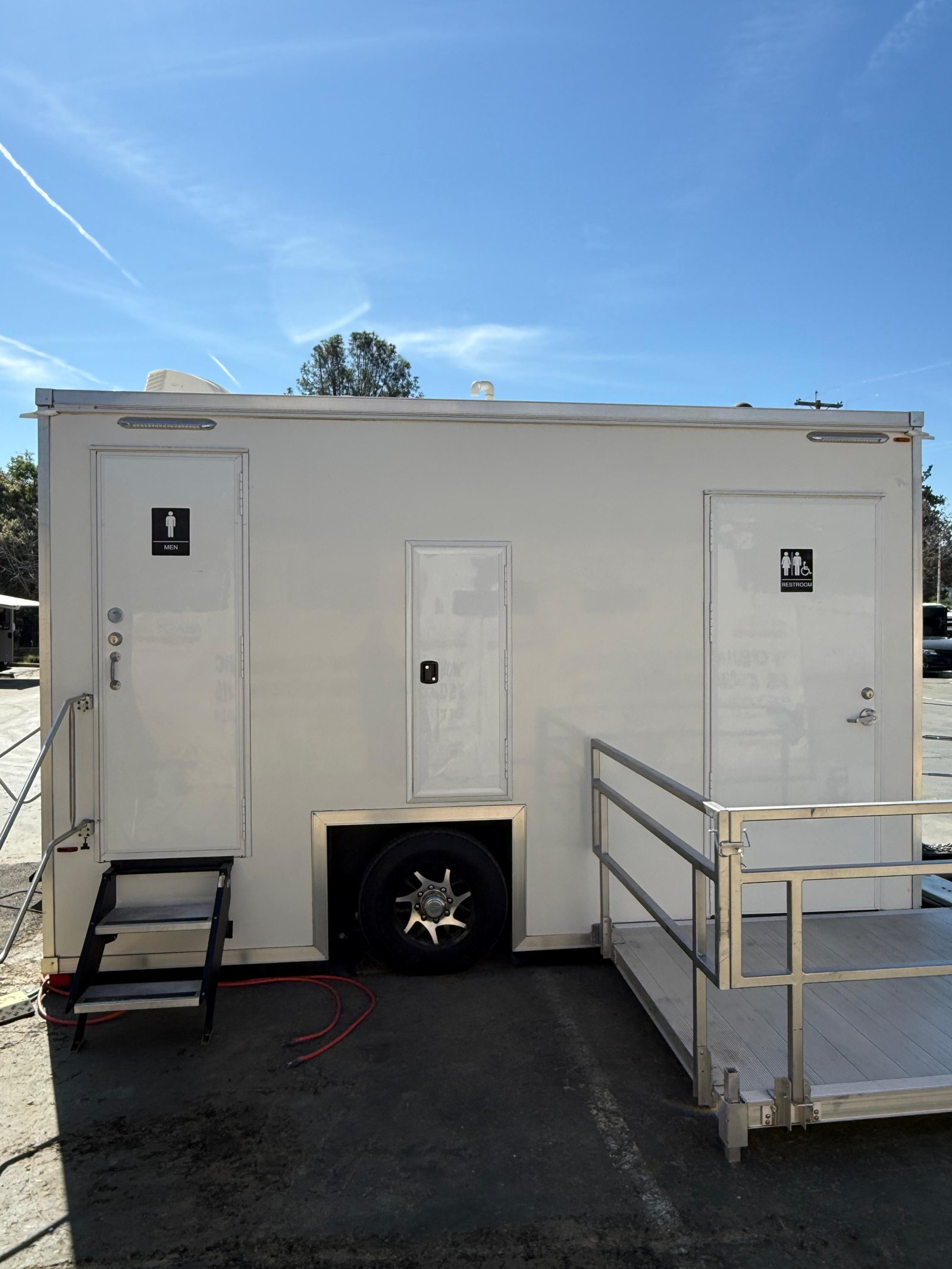 A Lavatory ADA + 2 restroom trailer with an aluminum ramp platform and rails at the accessible door
