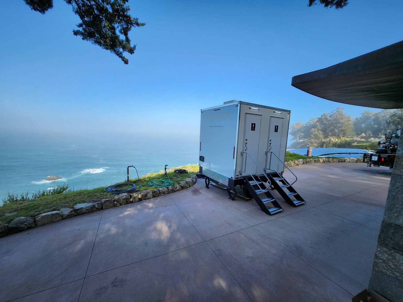 A Lavatory 2-Station restroom trailer on a concrete terrace above the ocean