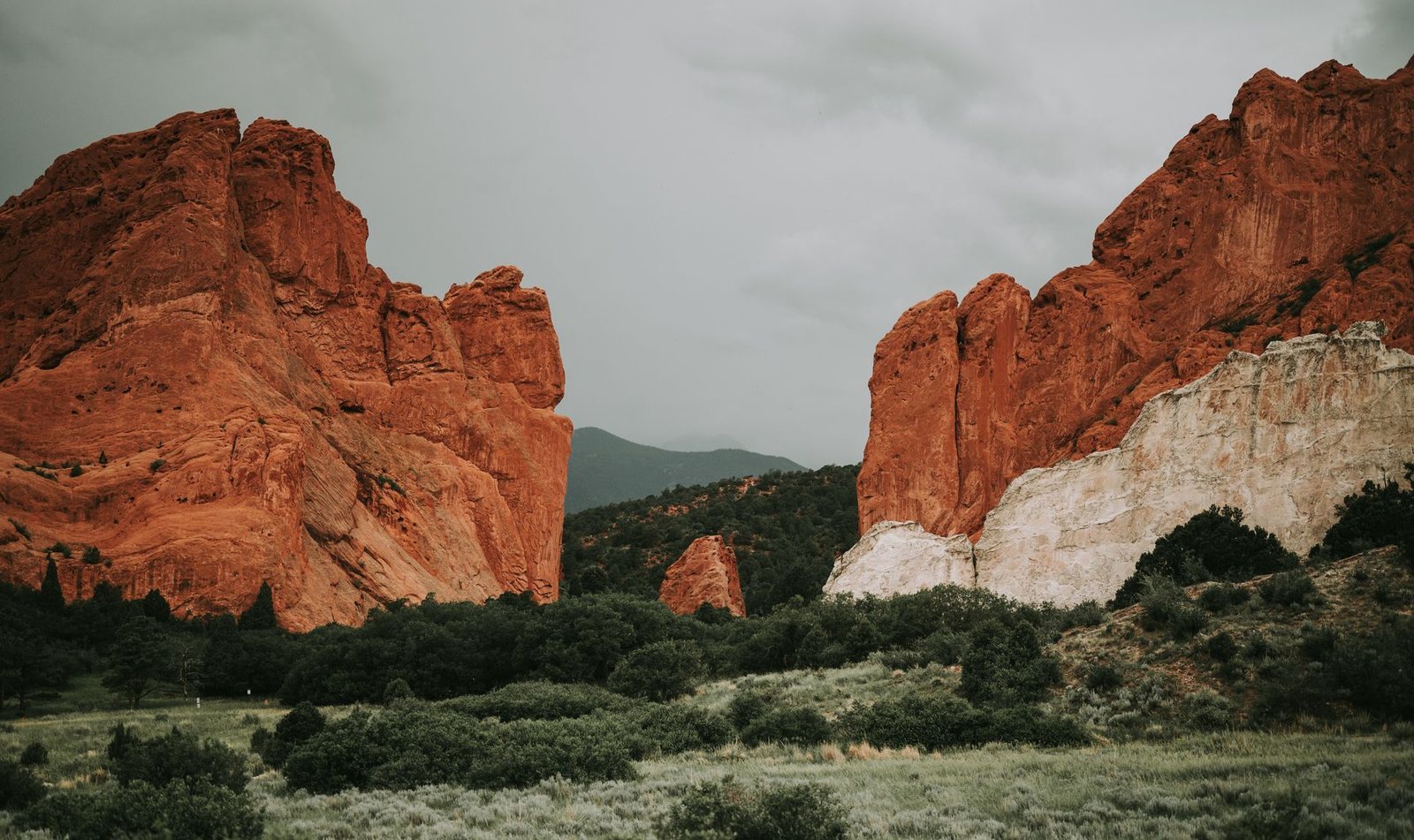 Red sandstone formations at Garden of the Gods in Colorado Springs under an overcast sky, with the foothills between them