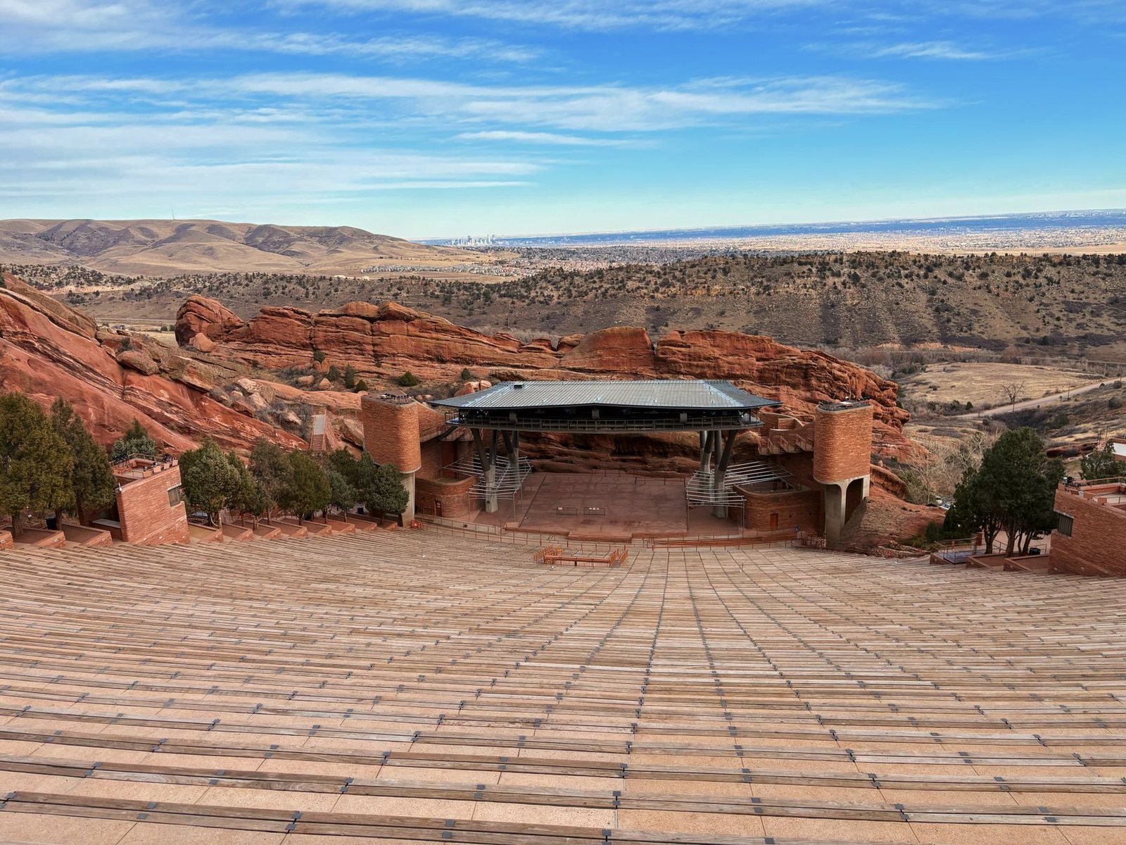 Empty rows of seating at Red Rocks Amphitheatre near Morrison, with the stage, red rock walls and the plains toward Denver behind