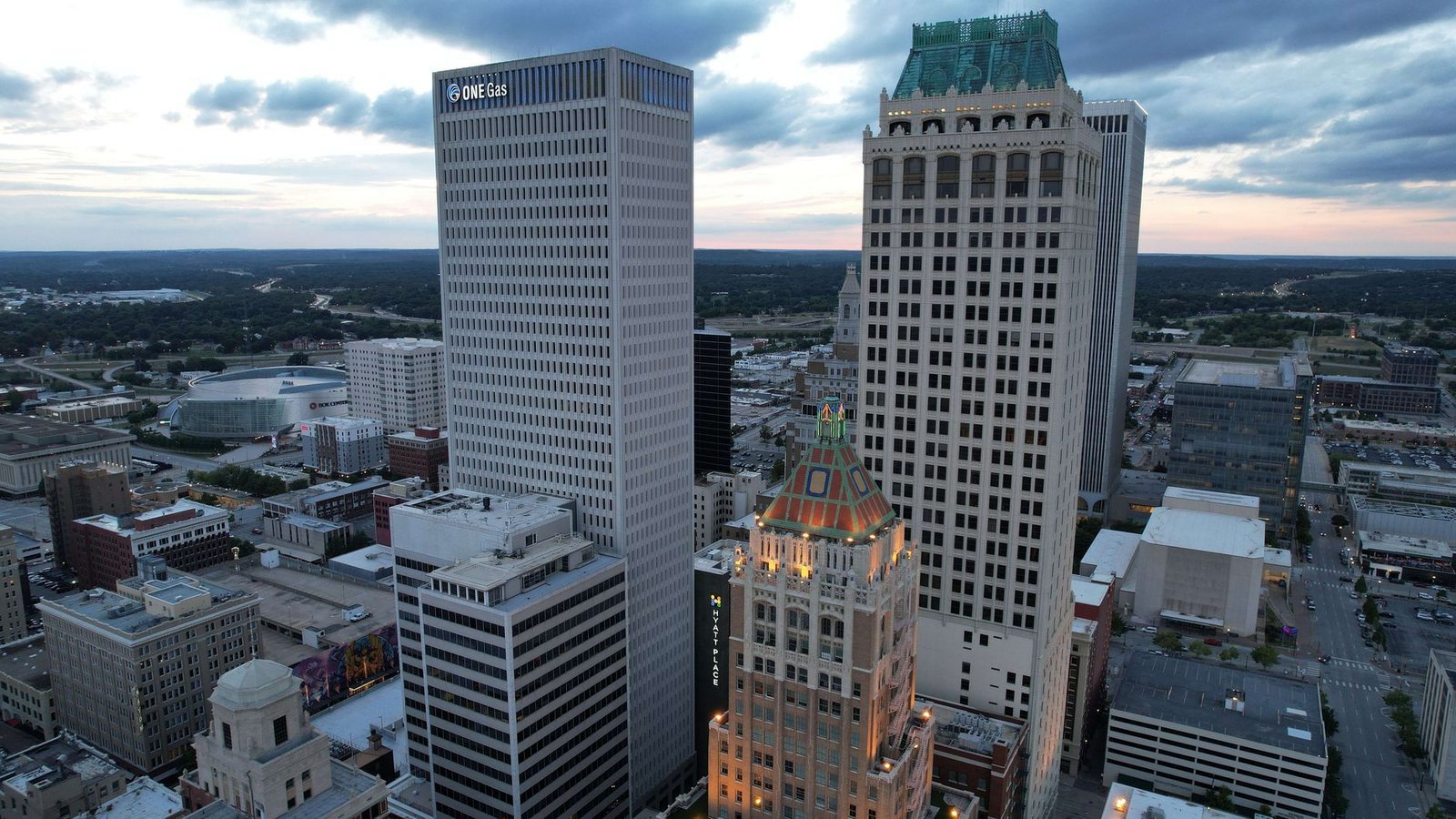 Downtown Tulsa at dusk from above, with the ONE Gas tower, the Philtower and the BOK Center arena below the skyline