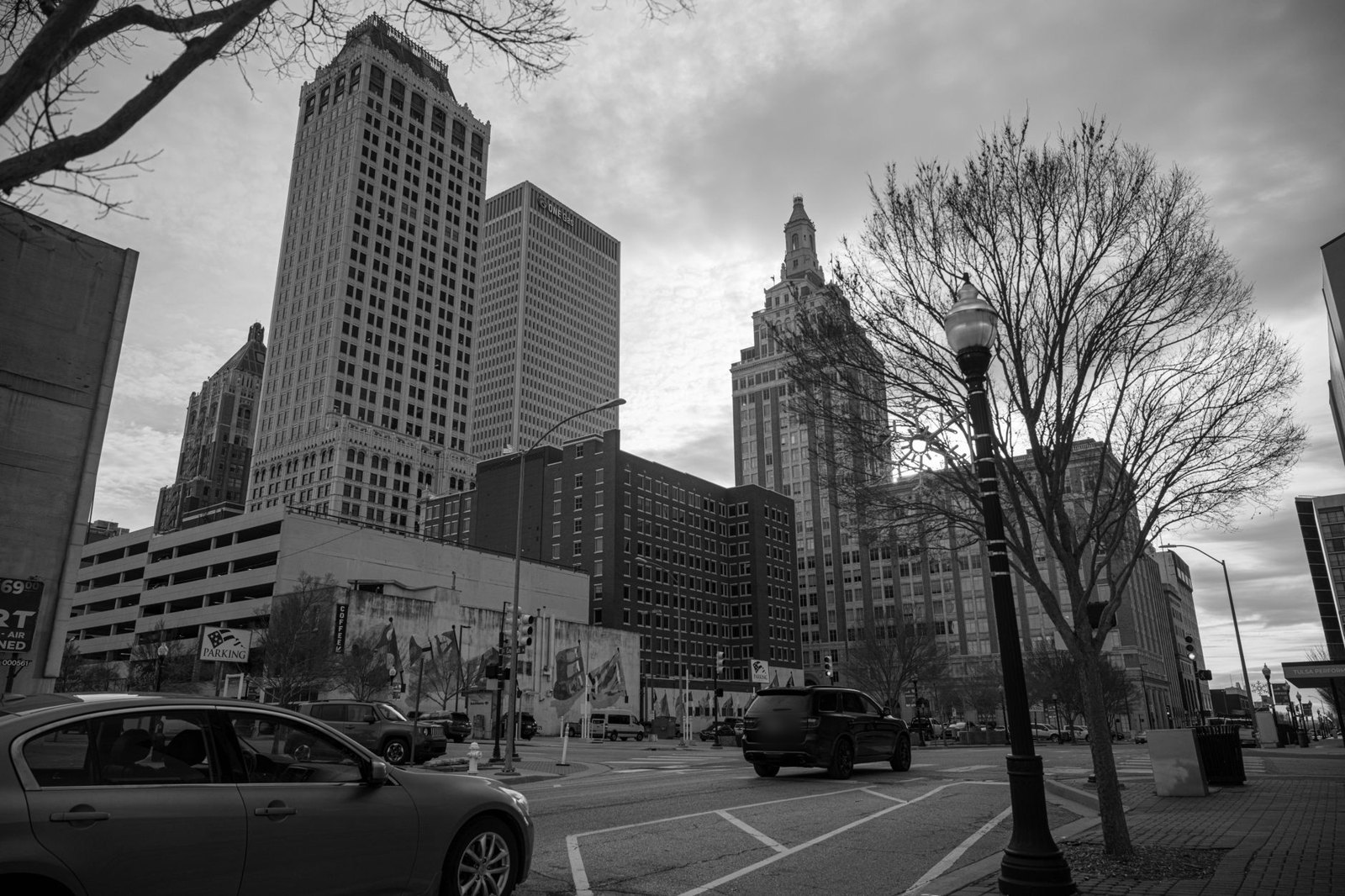 Downtown Tulsa office towers and a tree-lined street corner in black and white