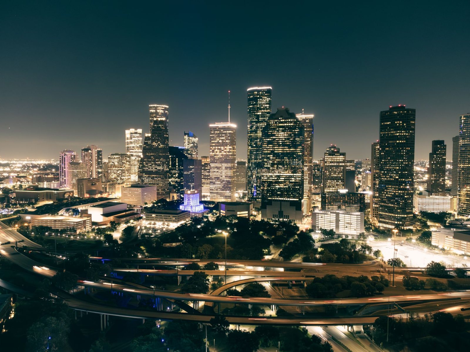 The downtown Houston skyline at night above lit freeway interchanges