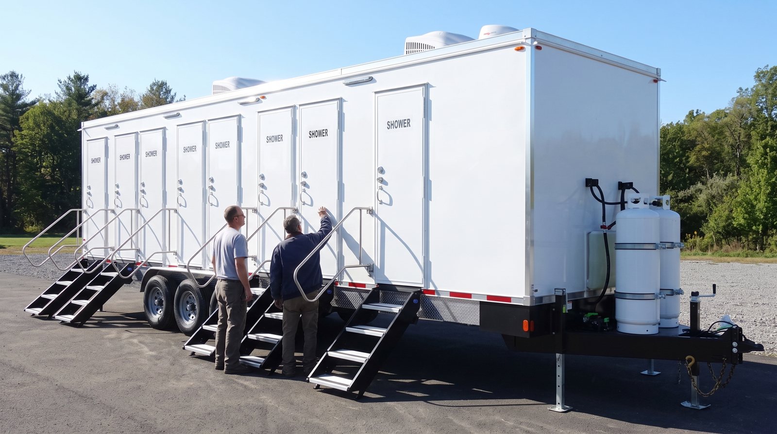 8-station shower trailer on a paved lot with two crew members inspecting a door