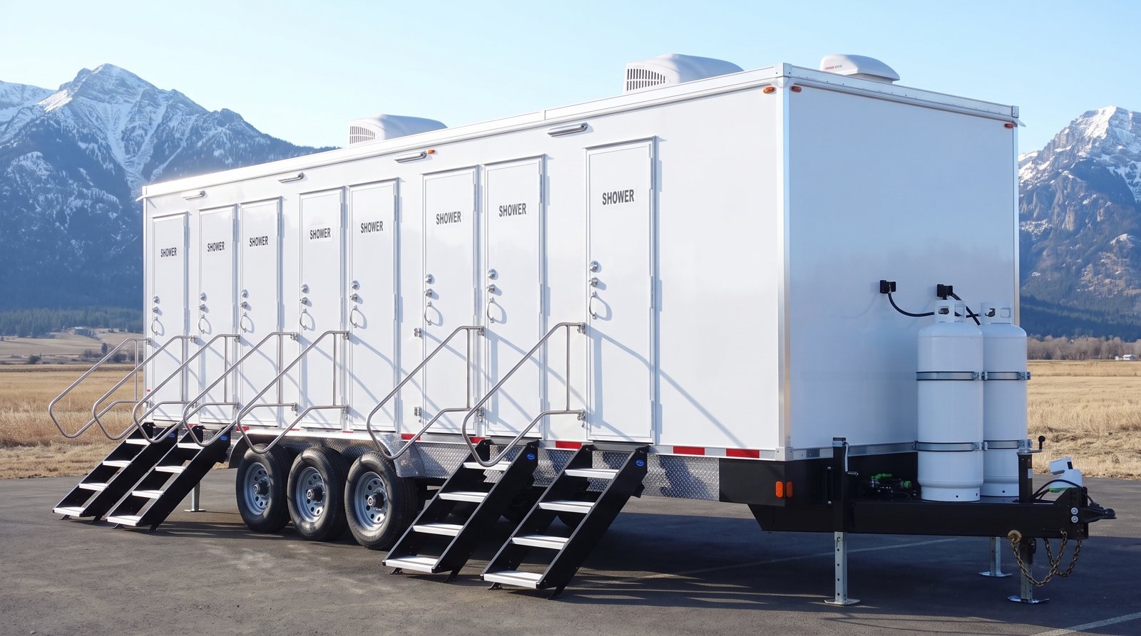 Private 8-station shower trailer on a paved lot with snow-capped mountains behind it, the kind of setting found around Bozeman, MT